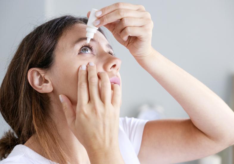 Woman placing eye drops in her eye